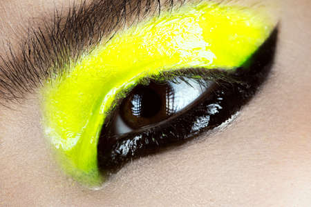 Close-up  yellow and black make-up creative art. Beauty face. Photo shot in studioの写真素材