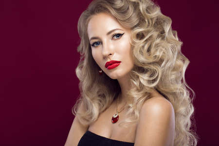 Beautiful blonde in a Hollywood manner with curls, red lips. Beauty face. Picture taken in the studioの写真素材