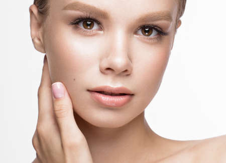 Beautiful young girl with a light natural make-up and French manicure. Beauty face. Picture taken in the studio on a white background.の写真素材