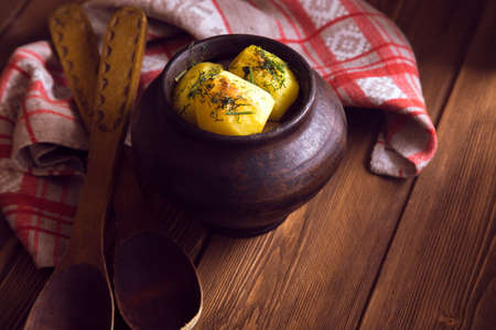 Baked potato in old pot on wooden background with pickled cabbage and cucumber.の写真素材