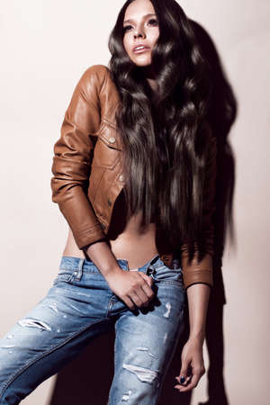 Attractive beautiful fashionable woman with curls unusual in everyday clothes, evening make-up, showing different poses in the studio. Beauty face and body. Test Shotsの写真素材