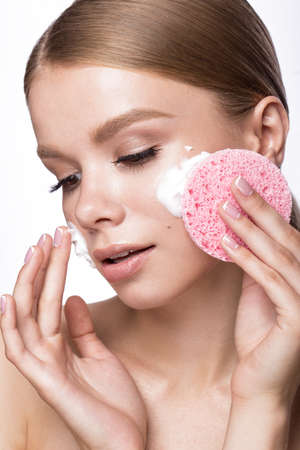 Beautiful young girl with sponge and foam cleanser and French manicure. Beauty face. Picture taken in the studio on a white background.の写真素材