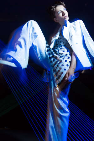 Fashion model beautiful girl in fashionable clothes in ultraviolet light, showing different poses....