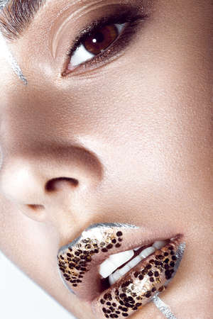 Portrait of a Beautiful fashionable girl with a creative glitter make-up and sparkles on the lips....