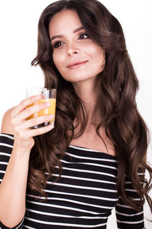 Beautiful woman with healthy skin, hair curls and orange juice posing in studio. Beauty faceの写真素材