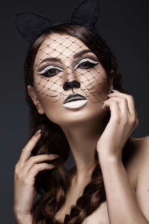 Beautiful girl in the image of a cat with art make-up and lace ears. beauty face. Photos shot in the studio.の写真素材