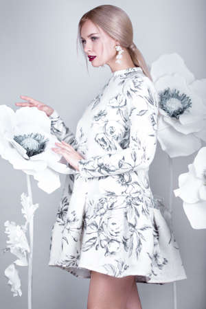 Beautiful girl with vintage make-up and hairstyle in a warm winter woolen dress. decoration of flowers. The beauty of the face. Photos shot in studioの写真素材