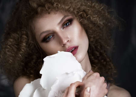 Beautiful girl with curly hair in lingerie with large flower. The beauty of the face. Photos shot in studioの写真素材