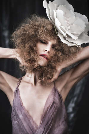 Beautiful girl with curly hair in lingerie with large flower. The beauty of the face. Photos shot in studioの写真素材