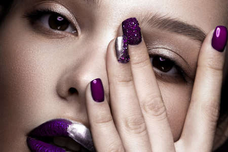 Beautiful girl with art make-up, dark glitter lips design and manicured nails. beauty face. Photos shot in studio. Close upの写真素材