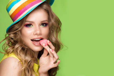 Bright cheerful girl in a summer hat, colorful make-up, curls and pink manicure. Beauty face. Photo...