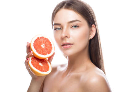 Beautiful young girl with a light natural make-up and perfect skin with Grapefruit in her hand. Beauty face. Picture taken in the studio on a white background.の写真素材