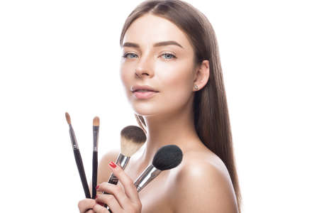 Beautiful young girl with a light natural make-up,brushes for cosmetics and perfect skin. Beauty...