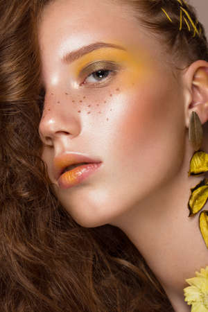 Portrait of beautiful red-haired girl with brightly colored art makeup and curls. Beauty face. Photo taken in the studio.の写真素材