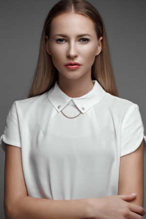 sexy fashion model with long hair, young European attractive, beautiful eyes, perfect skin is posing in studio for glamour vogue test photo shoot showing different poses. Picture taken in the studio on a gray background.の写真素材