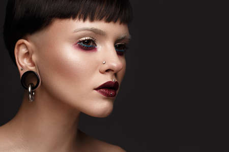 A beautiful girl with art creative make-up and earrings on the face. Photos shot in studioの写真素材