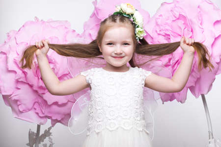 Little fairy girl in white dress on a background of flowers. Photo taken in studioの写真素材