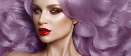 Beautiful woman in a Hollywood manner with color curls, natural makeup and red lips.. Beauty face and hair. Picture taken in the studioの写真素材