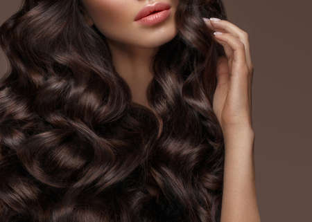 Beautiful brunette model with curls, classic makeup and full lips. The beauty of the face. Portrait shot in the studio.の写真素材