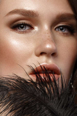 A beautiful girl with evening make-up, a Hollywood wave and a black pen in her hand. Beauty face. Photo taken in the studio.の写真素材