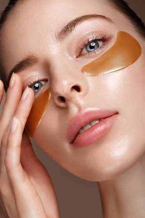 Beautiful fresh girl with cosmetic patches under the eyes, perfect skin and natural make-up. Beauty face. Photo taken in the studio.の写真素材