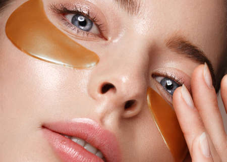 Beautiful fresh girl with cosmetic patches under the eyes, perfect skin and natural make-up. Beauty face. Photo taken in the studio.の写真素材