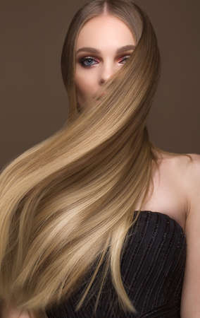 Beautiful blond girl with a perfectly smooth hair, classic make-up. Beauty face. Picture taken in the studio on a white background.の写真素材