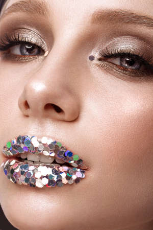 Beautiful girl with creative glitter make-up lips. Beauty face. Photos shot in studioの写真素材