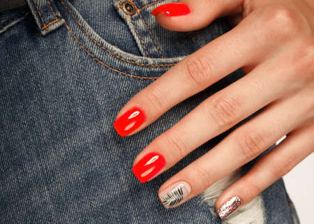 Bright neon red manicure on female hands on the background of jeans. Nail design. Beauty handsの写真素材