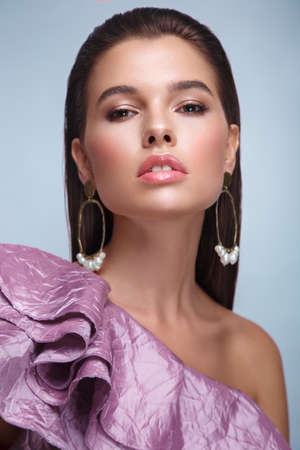 Beautiful fresh girl with classic make-up, smooth hair in a purple dress. Beauty face. Photo taken in studioの写真素材
