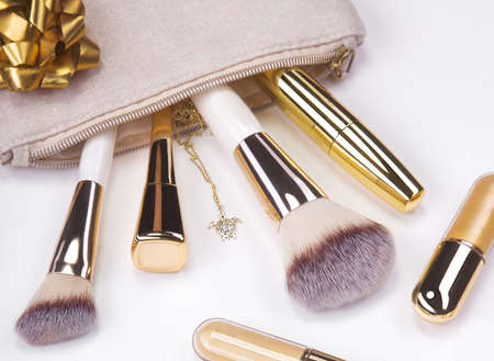 Set of brushes and cosmetic products in a cosmetic bag on a white background.の写真素材