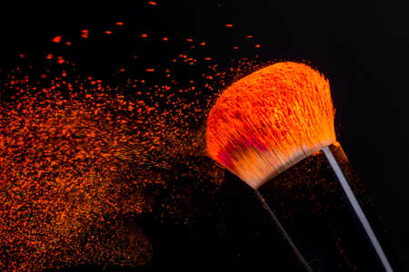 Cheek brush with neon cosmetic powder colorful spray and isolated on black backgroundの写真素材