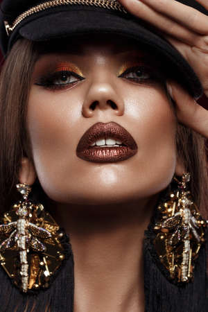 Beautiful brunette girl with curls, bright make-up and designer accessories. Beauty face. Photo...
