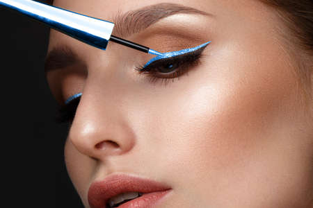 Beautiful girl with sexy lips and classic makeup with cosmetic blue eyeliner in hand. Beauty face....