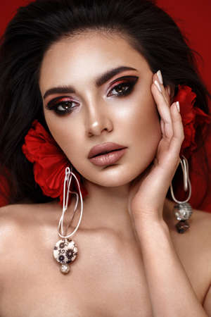 Beautiful girl with bright fashionable make-up and unusual red accessories. Beauty face. Photo taken in the studio.の写真素材