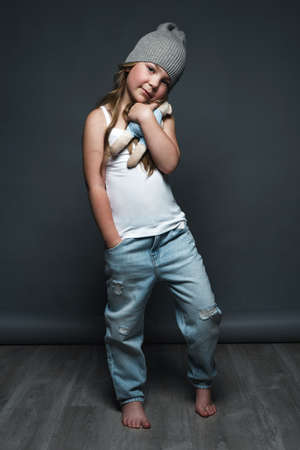 Little girl model professionally posing in the studio in jeans and a white T-shirt. Model tests.の写真素材