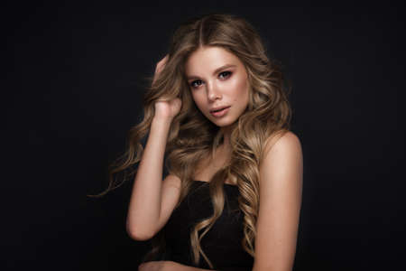 Beautiful blond girl with a perfectly curls hair, and classic make-up. Beauty face and hair.
