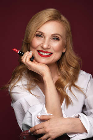 Portrait of a beautiful elderly woman in a white shirt with classic makeup and blond hair.の写真素材