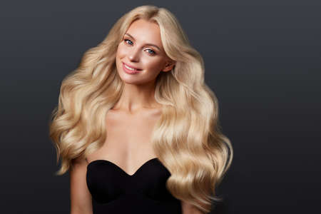 Beautiful blond girl with a perfectly curls hair, and classic make-up. Beauty face and hair.の写真素材