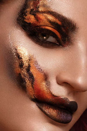Portrait of a beautiful woman with creative fire art make-up on her face.