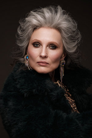 Portrait of a beautiful elderly woman in a leopard blouse and fur coat with classic makeup and gray...