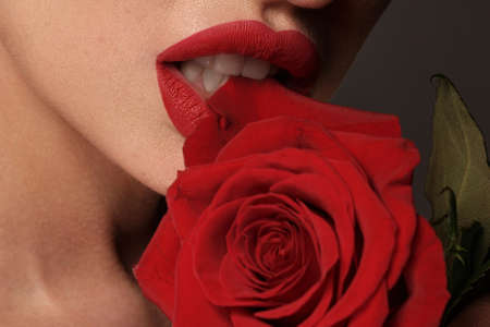 Beautiful brunette woman with red lips, holding flowers. The beauty of the face.の写真素材