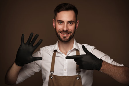 Manicur master man in working form in black gloves on hands. Nail photo content.の写真素材