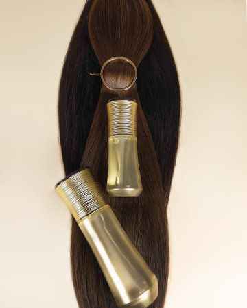 A strand of natural dark hair for extensions with a bottle of care product.の写真素材