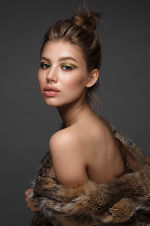 Portrait of a beautiful woman in a furcoat with creative gold makeup in a fashion style. Beauty face.の写真素材