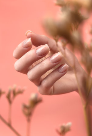 Gentle neat manicure on female hands on a background of dry flowers.の写真素材