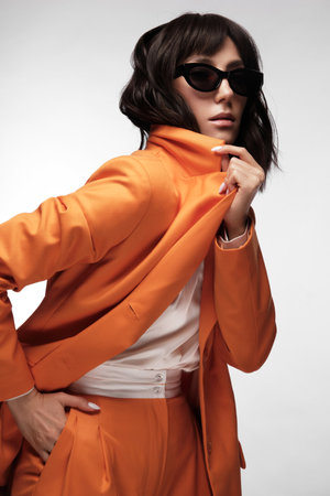 Spectacular beautiful woman in a trendy orange suit with classic make-up. Beauty face.の写真素材