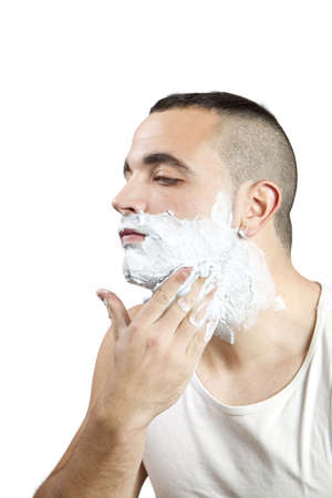 young man giving himself shaving cream on white backgroundの写真素材