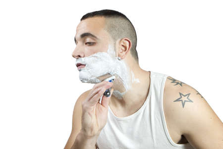 Young man shaving his beard with razor and foamの写真素材