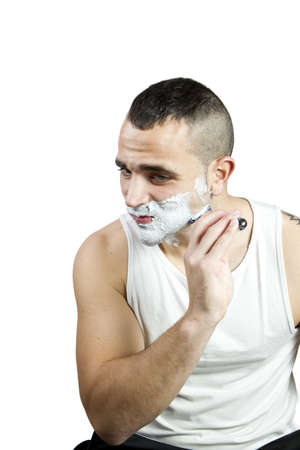 Young man shaving his beard with razor and foamの写真素材